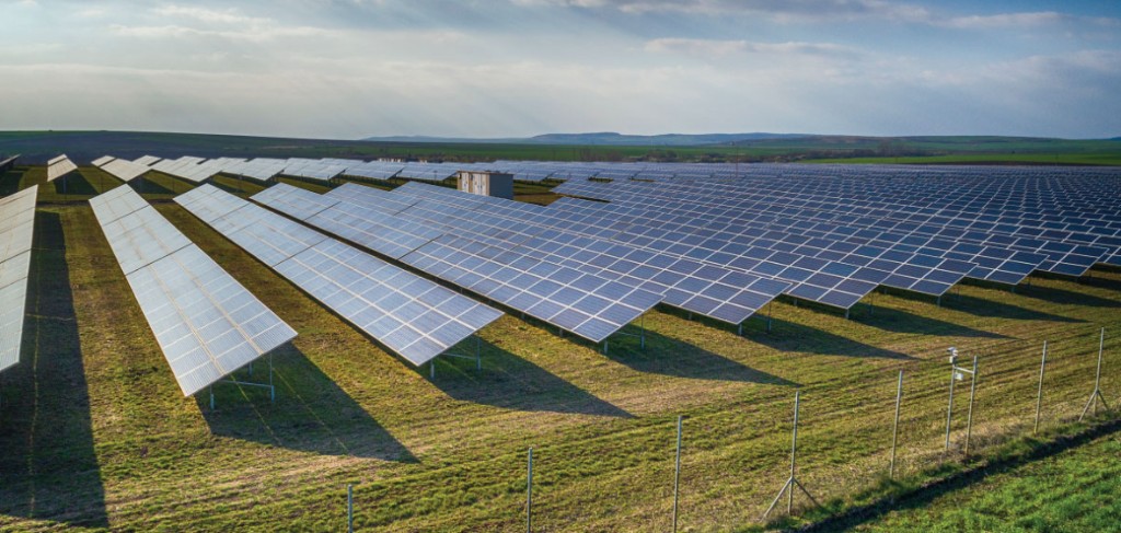 Solar farm with rows of photovoltaic panels in a grassy field